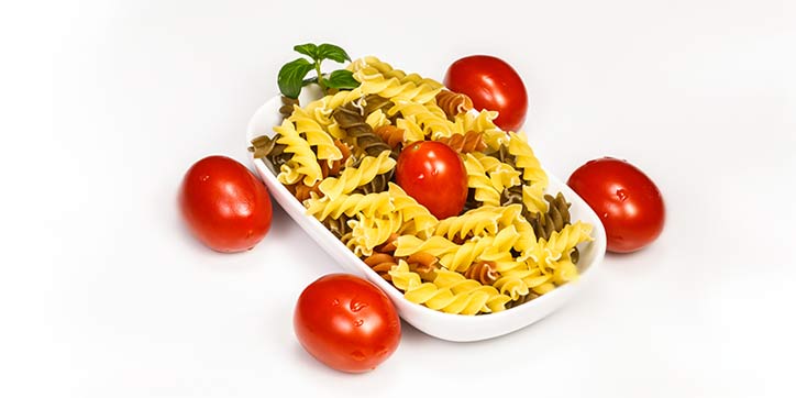 Pasta in a bowl shaped like a car with tomatoes as wheels