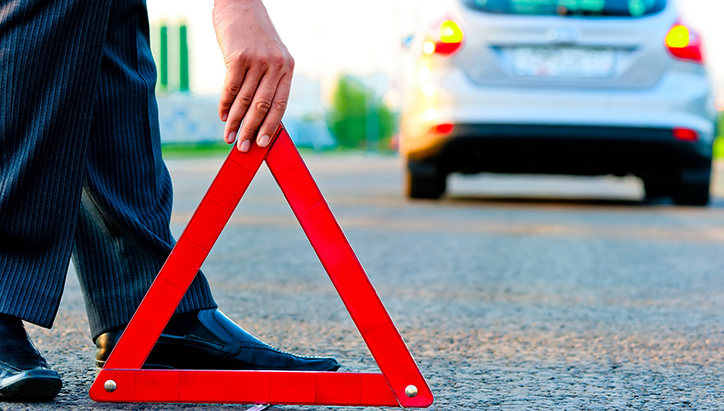 Person setting out warning triangle behind car