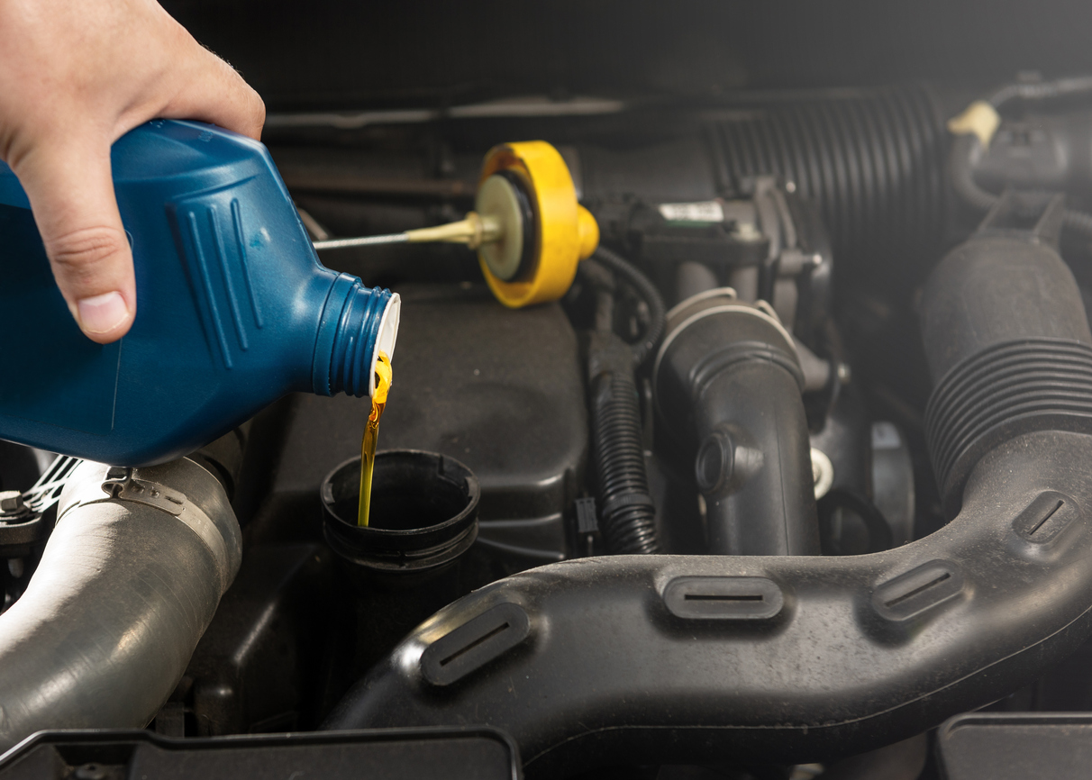 A person changes car's engine oil