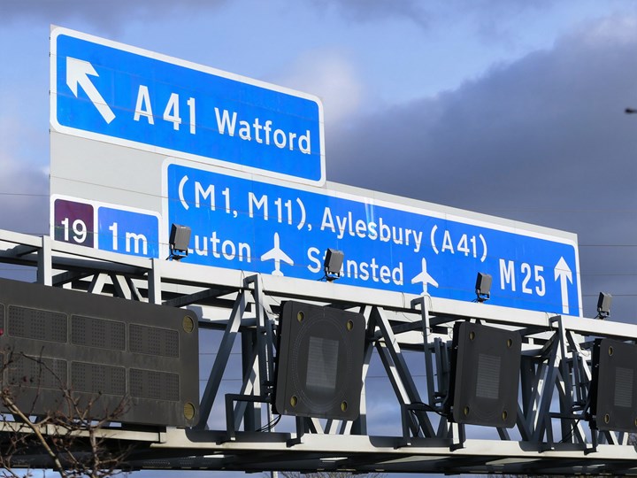 Blue road sign with arrow to Watford