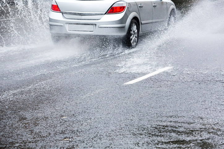 Car on very wet road splashing water as it drives through puddles