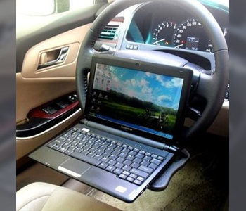 Laptop on a tray attached to a car steering wheel