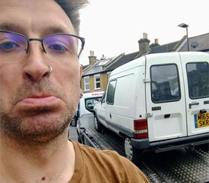 Man looking sad with an old van in the background