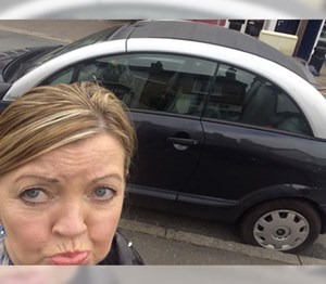 Woman looking sad and pouting stood with her old car