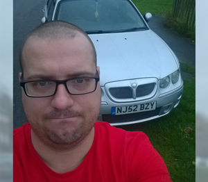 Man wearing glasses looking sad with his old car